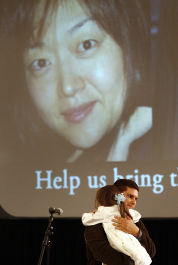 Lee's husband, Michael Saldate, holds daughter Hana during the vigil. (AP)