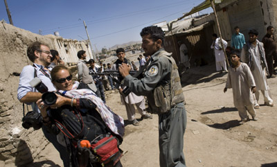 An Afghan police officer aims his weapon at two photographers covering pre-election violence in Kabul. (AFP/Pedro Ugarte)