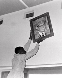 A Congolese man removes a portrait of Belgium's king in Leopoldville on July 22, 1960, at the end of colonial rule. (AP)