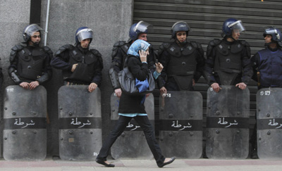 A woman walks past riot police standing guard during a demonstration in Algiers on Saturday. (Reuters/Louafi Larbi )