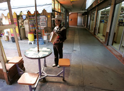 Javier Soto plays his accordion as he searches for tourists in a vacant downtown market in Nuevo Laredo on January 26, 2006. (AP/Gregory Bull)