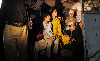 Students are taken away from a Karachi seminary where they were found in chains. Producers from Samaa TV who broke the story have been threatened. (AFP/Asif Hassan)