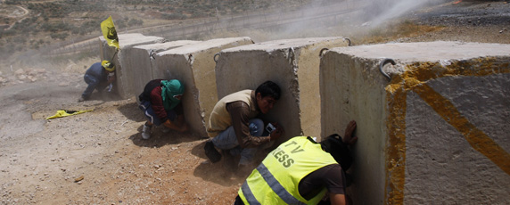 Un journaliste se tapit derrière un bloc de ciment lors d'affrontements entre forces israéliennes et manifestants palestiniens en Cisjordanie. (Reuters / Mohamad Torokman)