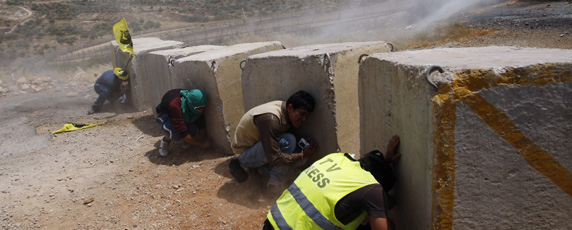 صحفي يجثم خلف حاجز إسمنتي أثناء مصادمات بين القوات الإسرائيلية ومتظاهرين فلسطينيين في الضفة الغربية. رويترز/ محمد تركمان