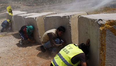 A journalist crouches behind a cement block during clashes between Israeli forces and Palestinian protesters in the West Bank. (Reuters/Mohamad Torokman)