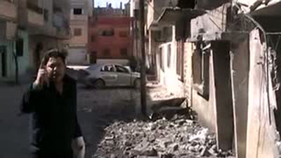 A Syrian man speaks outside a makeshift press center that was destroyed in a shell attack by government forces. Journalists wounded or killed in the Homs attack are not being allowed to evacuate. (AFP/YouTube)