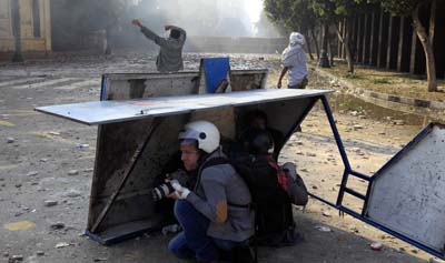 Photographers take cover behind a barricade during a protest in Egypt last year. Journalists are often forced to take deadly risks when working in war zones, usually with limited training and no insurance. (AFP/Mohammed Abed)