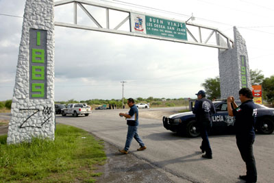 Investigators photograph graffiti implicating the Zeta cartel near where 49 corpses were found on the road near Monterrey, Mexico, on May 13. (AFP/Julio Cesar Aguilar)