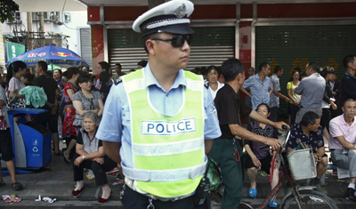 A police officer stands guard as protesters gather in the city of Shifang. (Reuters/Petar Kujundzic)