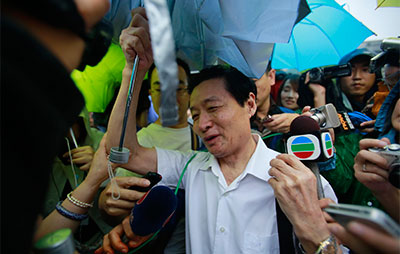 A spectator is surrounded by journalists Thursday after exiting the Hefei City Intermediate People's Court where the trial of Gu Kailai for murder takes place. (AP/Eugene Hoshiko)