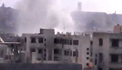 An image from a video published by the Shaam News Network shows smoke rising from buildings in Homs destroyed by government shelling. (AP/Shaam News Network)