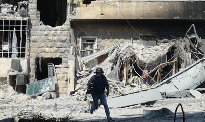 Un periodista esquiva disparos de armas de fuego en la ciudad de Alepo, en Siria. (AFP/Tauseef Mustafa)