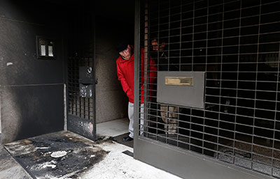 A resident stands at the burnt entrance of a building following a series of attacks against journalists in Athens on Friday. (Reuters/John Kolesidis)