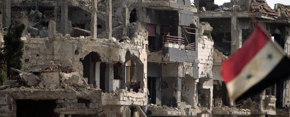 A flag flies next to a building destroyed by shelling in the city of Baba Amr. (AFP/Joseph Eid)