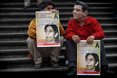 Two men, one wearing a mask depicting President Enrique Peña Nieto, protest to demand justice in the Regina Martínez case a year after her murder on April 28. (AP/Felix Marquez)