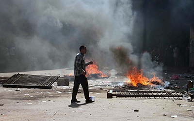 An Egyptian citizen walks near fires in Cairo's Ramses square. Clashes between police and supporters of ousted President Mohamed Morsi have broken out across the country. (AFP/Khaled Kamel)