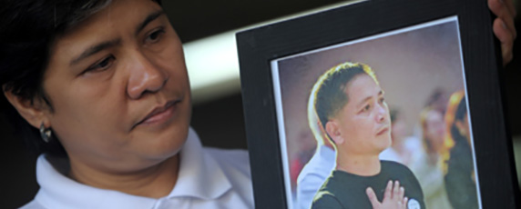 Patricia Ortega is shown holding a photo of her husband, murdered radio host Gerardo Ortega. A witness to Ortega's 2011 killing was found dead in his jail cell in 2013. (AFP/Noel Celis)