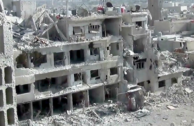 Uma imagem feita pela Shaam News Network, uma organização de notícias cidadã baseada em Damasco, mostra edifícios danificados por bombardeio pesado.(AP/Shaam News Network)