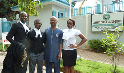 The son of the late journalist Deyda Hydara, in blue, stands outside the ECOWAS court with his lawyers. (CPJ/Peter Nkanga)