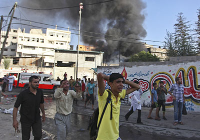 Palestinian citizens react to an air strike dropped by the Israel Defense Forces on a market in the Shijaiyah neighborhood of Gaza. A journalist was killed in the attack. (Reuters/Ashraf Amrah)