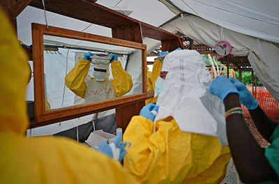 Health workers in Sierra Leone put on protective clothing. The government there has joined forces with the press to raise awareness about Ebola. (AFP/Carl de Souza)