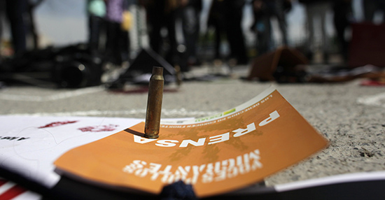 A bullet shell is seen standing on press accreditation, surrounded by journalists protesting the murder of reporters in Mexico. (Reuters/Daniel Becerril)