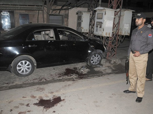A police officer stands guard next to the car Pakistani journalist Raza Rumi was in when gunmen opened fire on him and killed his driver, Mustafa, in March 2014. (Tariq Hasan/Express Tribune)