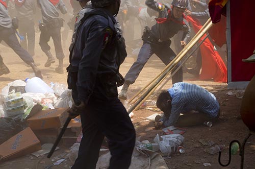 A police officer is seen beating a student protester in Letpadan on Tuesday. Journalists covering the protest were harassed, attacked, and detained by police. (AP/Gemunu Amarasinghe)