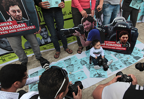 The infant son of Ahmed Humaidan is surrounded by fliers at a rally for the jailed journalist in 2014. The photographer is one of at least five journalists held in Jaw Prison. (AP/Hasan Jamali)