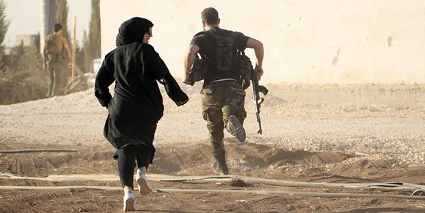 Une journaliste se exécute avec un combattant rebelle tout en évitant les tireurs embusqués près d'Alep, en Syrie, le 10 octobre, 2014. (Reuters / Jalal Al-Mamo)