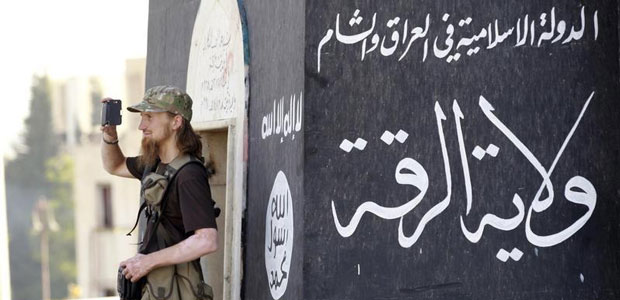 Un islamista radical utiliza un teléfono móvil para filmar a otros combatientes del Estado Islámico que participan en un desfile militar por las calles de las ciudades de la provincia siria de Raqqa el 30 de junio de 2014. (Reuters)