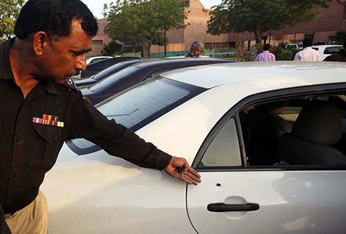 A police official points to bullet holes in Hamid Mir's car following the attack on him in April 2014. (Reuters/Athar Hussain)