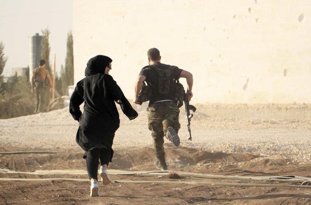 A female reporter runs with a rebel fighter while evading snipers near Aleppo, Syria, October 10, 2014.