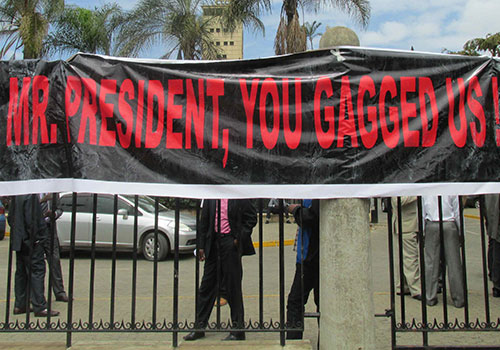 Journalists hang a banner over railings as part of a protest against repressive media laws in December 2013. (CPJ/Tom Rhodes)