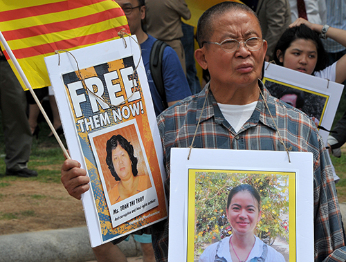 Pictures of Vietnamese political prisoners are waved at a rally outside the White House in July to protest Trong's visit with President Obama. (AFP/Mladen Antonov)