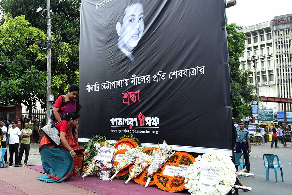 Des fleurs sont déposées en hommage sous une photo de Niloy Neel en août. Neel est le quatrième blogueur tué à coups de machette par des extrémistes au Bangladesh en 2015. (AFP/ Munir uz Zaman)