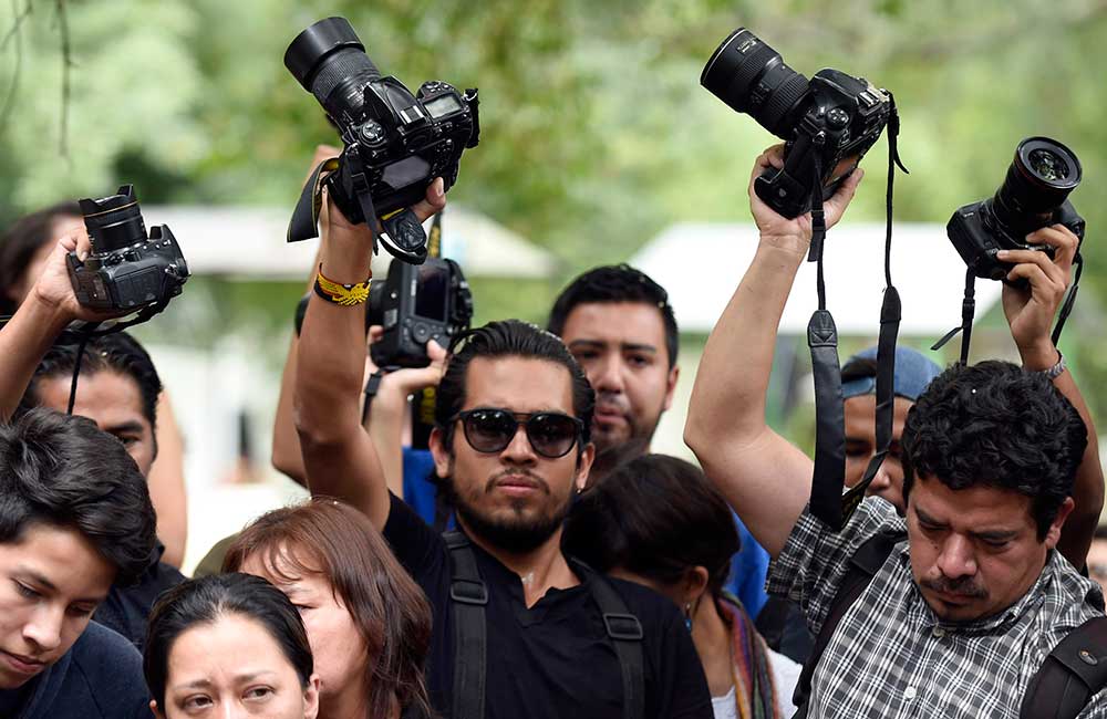 Des amis et collègues de Rubén Espinosa soulèvent leurs appareils photo lors de l'enterrement du photographe, assassiné à Mexico. Le taux d'impunité du Mexique a presque doublé depuis 2008. (AFP/Alfredo Estrella)