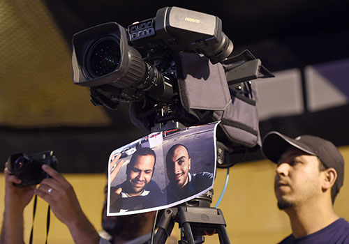An image of Sofiene Chourabi and Nadhir Guetari hangs from a camera in May. The Tunisian government is accused of being opaque about the case of the journalists, who Islamic State claims to have killed in Libya. (AFP/Fethi Belaid)