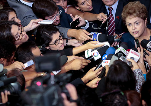 Gazeteciler Brezilya Başkanı Dilma Rousseff'in etrafını sarmış. Brezilyalı yetkililer yakın zamanda gerçekleşen çok sayıda mahkumiyet ile cezasızlık ile mücadelede aşama kaydettiler fakat 2015 yılında daha önce görülmemiş bir sayı olan altı gazeteci cinayeti yaşandı. (AFP/Wenderson Araujo)