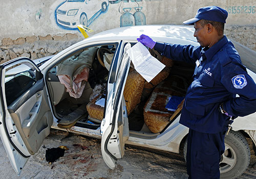 Сотрудник сил безопасности проводит следственные действия по делу об убийстве сомалийской журналистки Хиндии Хаджи Мохаммед, погибшей при взрыве бомбы, подложенной ей в автомобиль в декабре. (AFP/Мохаммед Абдивахаб)