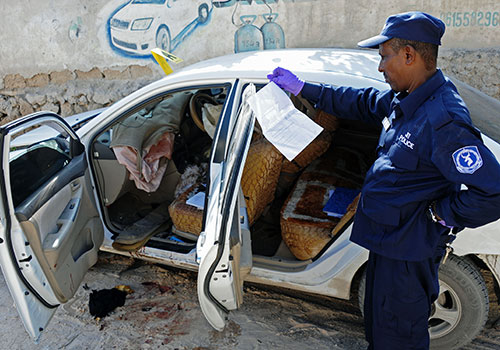 ضابط أمن يحقق في جريمة قتل الصحفية الصومالية هندية حاج محمود، والتي قتلت بتفجير قنبلة في سياراتها. (وكالة الأنباء الفرنسية/ محمد عبد الوهاب)