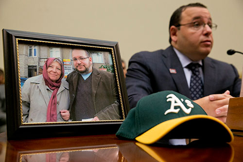 Ali Rezaian sentado junto a una foto que muestra a su hermano, el periodista del Washington Post Jason Rezaian, y a la madre de ambos, durante una audiencia de la Comisión de Relaciones Exteriores de la Cámara de Representantes para personas con familiares encarcelados en Irán. (AP/Jacquelyn Martin)