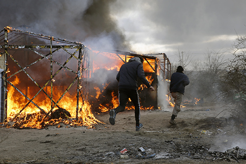 Tents are burned as the makeshift refugee camp known as the Jungle, in Calais, is dismantled. Reporters covering the French site say they have been attacked. (AP/Jerome Delay)
