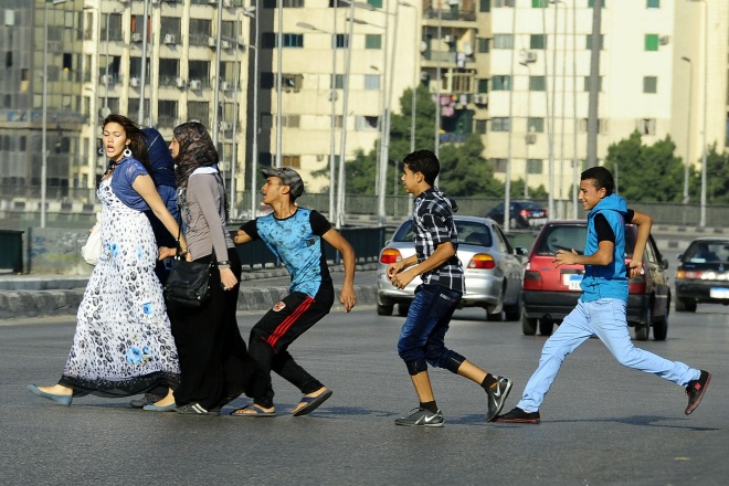 Um jovem egípcio agarra uma mulher ao cruzar uma rua com amigas, no Cairo em 2012.  Várias mulheres jornalistas foram agredidas na praça Tahrir depois da queda de  Hosni Mubarak. (AP/Ahmed Abdelatif, jornal El Shorouk)