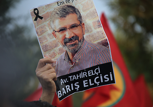 A poster is held up of Tahir Elçi, a lawyer shot dead in Turkey last year. A reporter for DİHA was questioned this week for "insulting the president" after allegedly sharing a political cartoon about the lawyer's death. (AP Photo/Mahmut Bozarslan)