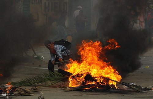 Un manifestante del CNTE se agacha cerca de una barricada durante los enfrentamientos con la policía antidisturbios en Nochixtlán. Periodistas que cubren los disturbios dicen que han sido acosados y atacados. (Reuters/Jorge Luis Plata)