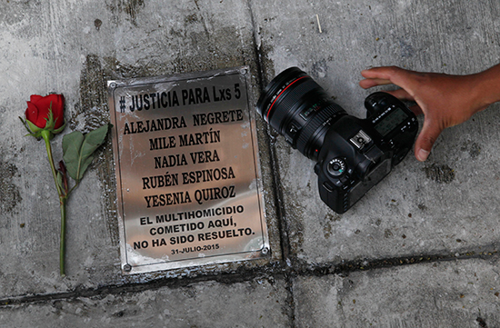 A photographer sets his camera beside a plaque commemorating photojournalist Ruben Espinosa and four women murdered with him in Mexico City in 2015 on the anniversary of their deaths, July 31, 2016. Espinosa worked with the investigative magazine Proceso and other media in the state of Veracruz at the time of his murder. (AP/Marco Ugarte)