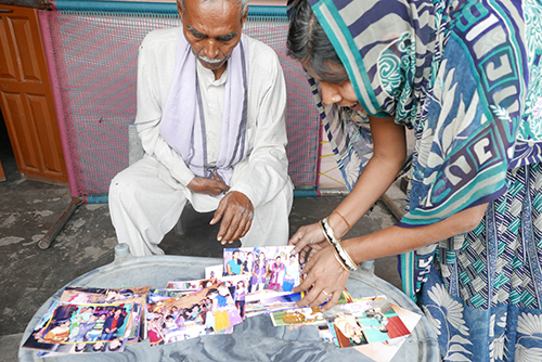 Sumer Singh and his son’s widow, Suman, look through family photos of Jagendra. “He was fearless,” the journalist’s father said. (CPJ/Sumit Galhotra)