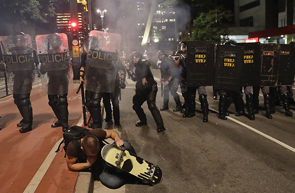 A protester takes cover as police throw tear gas during protests in August over the impeachment of Dilma Rousseff. Journalists have been caught in the crossfire of Brazil's political unrest. (AP/Andre Penner)