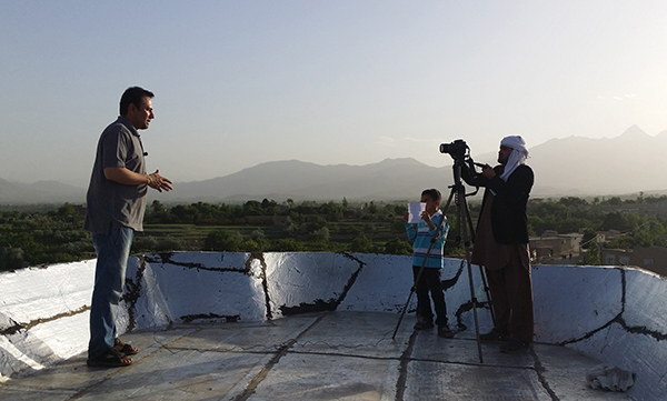 O jornalista afegão Zabihullah Tamanna, a esquerda, realiza transmissão nos arredores de Cabul em maio de 2015. Tamanna e o repórter norte americano David Gilkey foram mortos em 2016 enquanto trabalhavam para a NPR. (AFP/Parwiz Sabawoon)